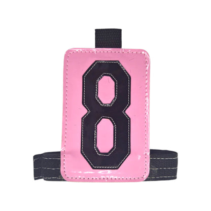 Pink luggage tag with black number 8 and a gray strap.